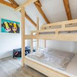 Zimmer mit Holzbett, Wandbild von Kühen und Holzbalkendecke.