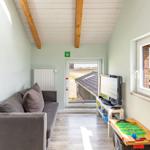 Wohnzimmer mit Sofa, Fernseher und Tischfußball. Fenster und Tür zeigen auf Felder.