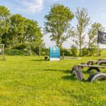 Grüner Spielplatz mit Klettergerüst, Schaukel und Piratenflagge. Spielplatz mit Sandkasten und Fußballtor.