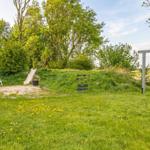 Grüner Garten mit Spielplatz, Rutsche und Schaukel. Spielhaus und Sandkasten sind vorhanden.