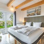 Schlafzimmer mit Doppelbett, Holzbalkendecke und Blick auf Garten