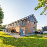 Moderne Ferienhaus mit Garten, Grillplatz und Pool. Holztische und Stühle im Freien.