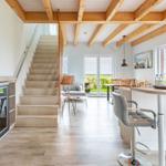 Haus mit offener Küche, Holzdecke und Treppe zur oberen Etage.