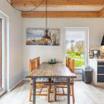 Essbereich mit Holztisch, Stühlen und Küchenzeile. Holzdecke und Fenster zur Außenterrasse.