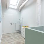 Raum mit Holzboden, weißer Tür und Dachfenster. Kleiderständer und Schrank sind vorhanden.