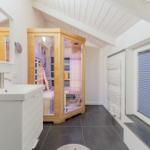 Dusche mit Sauna, Waschbecken und Heizkörper an der Wand.