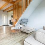 Wohnzimmer mit Sofa, Fernseher und Holzstufenhaus unter Dachschrägen.