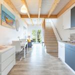 Küche mit Arbeitsplatte, Treppe und Essbereich mit Tisch und Stühlen.