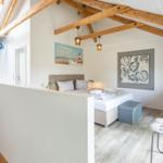 Schlafzimmer mit Dachschrägen, Bett, Stuhl und Wandbildern.