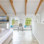 Schlafzimmer mit Bett, Fernseher und zwei Fenstern mit Blick auf Balkon.