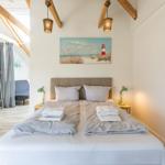 Doppelbett mit Handtüchern, Wandbilder und Holzbalken an der Decke.