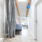 Schlafzimmer mit Bett, Garderobe und Fensterblick auf Felder.