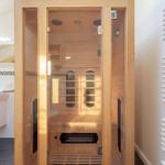 Sauna mit Holzverkleidung und Glasfront. Neben dem Waschbecken ist eine Heizung angebracht.