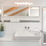 Bad mit Waschtisch, Spiegel und Dusche unter Holzdecke