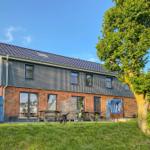 Moderne Ferienhaus mit Terrasse, Picknicktischen und Strandkörben im Grünen.