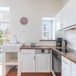 Kitchen with white cabinets, wooden countertops, and view to the terrace.