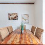 Dining room with wooden table, wicker chairs, and seashell pictures on the wall.