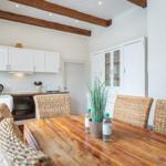 Kitchen with dining area, white cabinets, and rustic wooden table with chairs.