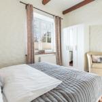 Bedroom with bed, window, wardrobe, and armchair.