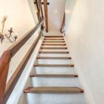 Wooden staircase with rope mat leads upward. A lantern hangs on the wall.