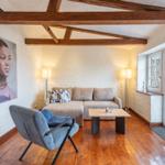 Living room with wooden beams, sofa, armchair, and large window.