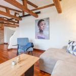 Living room with sofa, chair, table, and wooden beam ceiling.