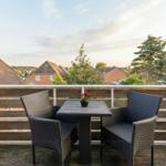 Terrace with table and two chairs, view of rooftops and trees.