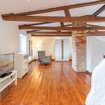 Room with wooden beams, hardwood floor, and TV on white stand.