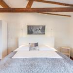 Bedroom with bed, wardrobe, and wooden beams on the ceiling.