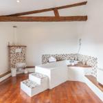 Bathroom with bathtub, toilet, and wooden beams on the ceiling.