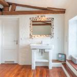 Bathroom with sink, mirror with mosaic frame, and window with seat bench.