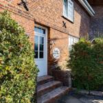 Entrance of a brick house with white doors and plants