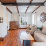 Living room with wooden floor, fireplace, sofa, and wall clock.