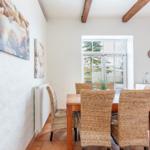 Dining room with wooden table, wicker chairs, and window to the garden.