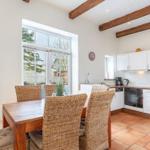 Kitchen with dining area, white cabinets, and wooden beams on the ceiling.