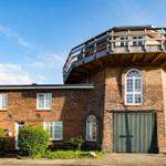 Two-story brick house with wooden terrace and green garage door.