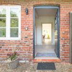 Entrance with red brick house, door, and window. View inside.