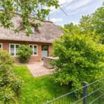 House with thatched roof, garden, and terrace with seating area.