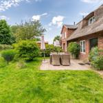 Rear yard with patio, garden, and thatched house.