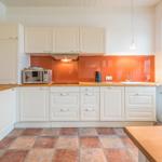 Küche mit weißen Schränken, orangefarbener Rückwand und Holzoberflächen.