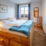 Ein Schlafzimmer mit Holzbett, blauen Vorhängen und Stuhl neben dem Fenster.