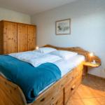 Schlafzimmer mit Holzbett, Kleiderschrank und Nachttischlampe.