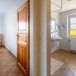 Schlafzimmer mit Bett und Spiegel. Nebenraum ist Bad mit Waschbecken und Toilette.