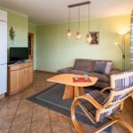Wohnzimmer mit Sofa, Tisch und Stuhl. An der Wand hängt ein Fernseher.