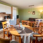 Küche mit Essbereich und Wohnzimmer mit Sofa und Holztisch.