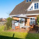 Haus mit Terrasse, Sonnenschirm, Tisch und Stühlen im Garten.