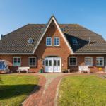 Red brick house with dormers and white door. Lawn and stone path in front.