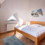Bedroom with sloped ceiling, bed, TV, and window.