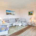 Wohnzimmer mit Sofa, Sessel, Couchtisch und Fernseher.