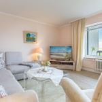 Wohnzimmer mit Sofa, Fernseher und großem Fenster mit Blick auf Landschaft.